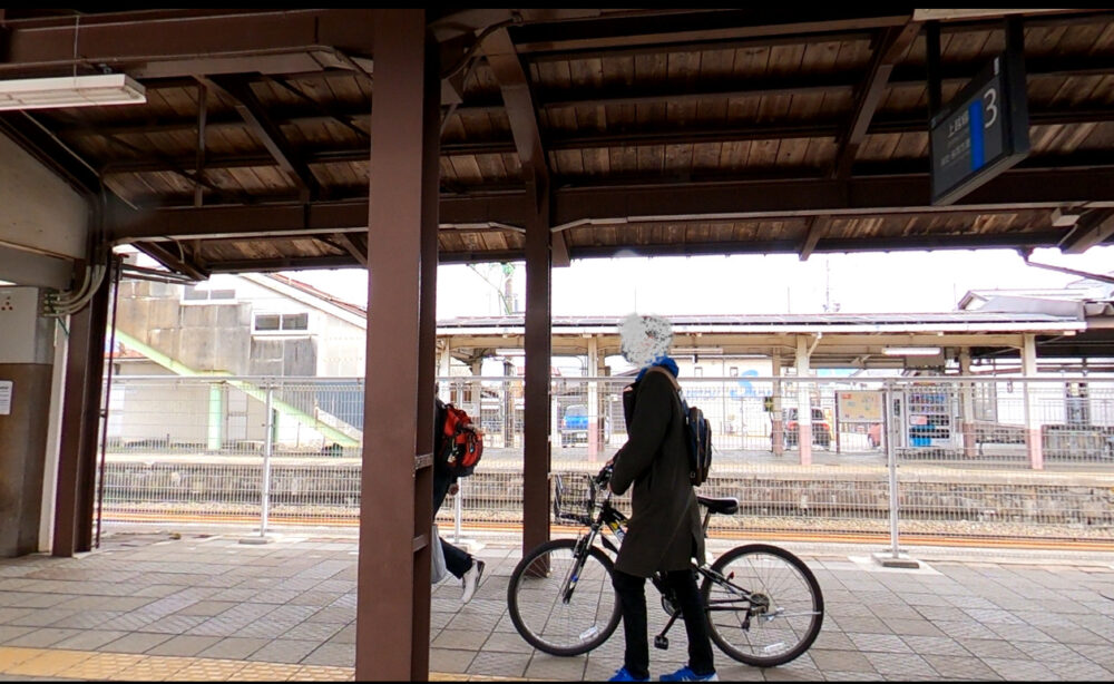 電車を降り自転車を押して歩く少年